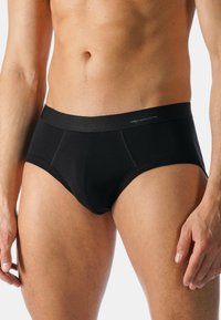 Svarta bomullsboxershorts med en mjuk midjeresår och en slät textur, med en figurnära silhuett och minimala sömnadsdetaljer på framsidan.