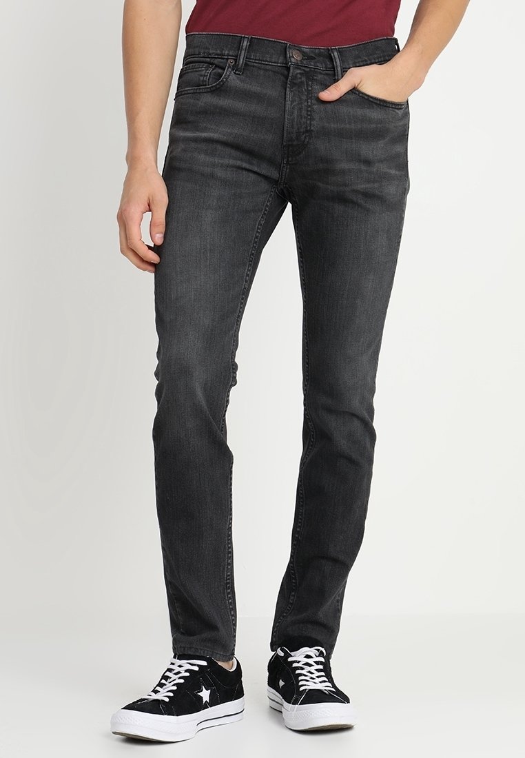 Svarta denimjeans med rak passform, femfickorsdesign och dragkedja. Bärs med svarta sneakers med vita detaljer.