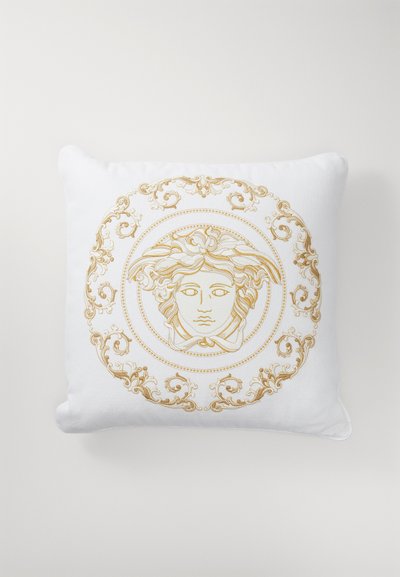 Bela blazina z zlatim vezenim dizajnom obraza, obdanim z okrasnimi vzorci. Mehka tekstura z zaobljenimi robovi.