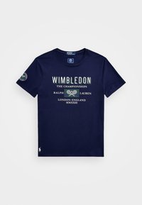 Námořnick á modrá tenisová tričko s tématem Wimbledonu, s logem zkřížených raket a textem "Šampionát Ralph Lauren Londýn Anglie MMXXIII."