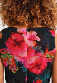 Kwiatowa sukienka na czarnym tle, zdobiona dużymi wzorami hibiskusa w odcieniach różu i czerwieni. Gładki materiał z zamkiem błyskawicznym z tyłu.