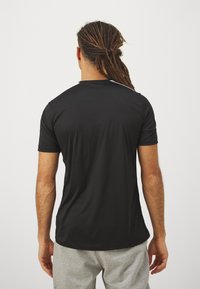 Camiseta atlética negra de manga corta, hecha de una tela ligera, con un escote redondo y acentos en blanco en los hombros.