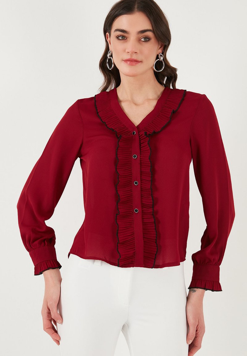Rode blouse met gerimpelde halslijn en voorkant, zwarte afwerking, lange mouwen met gathered manchetten en knoopdetails, gemaakt van lichtgewicht stof.