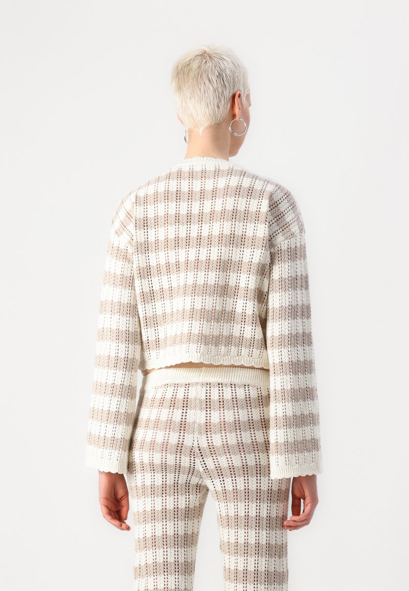 Gekürzter Strickpullover mit einem hellbeige-weißen gestreiften Muster. Verfügt über lange Ärmel und einen gerippten Saum, der ein strukturiertes Gewebe zeigt.