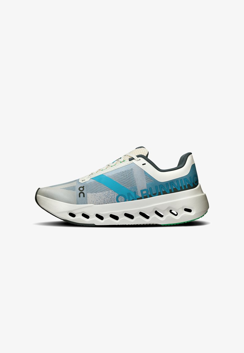 Hellgrau Sport-Schuh mit einem blauen diagonalen Streifen, Obermaterial aus Mesh, gepolsterter weißer Sohle mit Belüftungsöffnungen und grünen Akzenten.