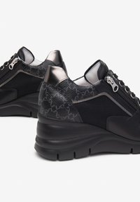 Baskets noires avec un mélange de cuir lisse et de mesh. Dotées d'un accent métallisé, d'une fermeture éclair et d'un talon texturé pour un soutien supplémentaire.