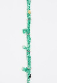 Braccialetto intrecciato realizzato in tessuto verde con anelli argentati e una perla gialla, con estremità sfrangiate e un accento di perla scura e liscia.