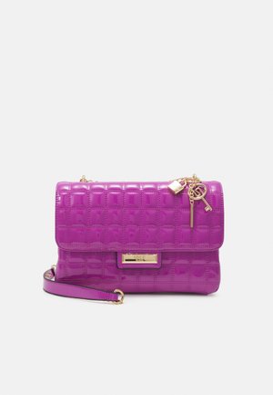 Sac à main matelassé violet brillant avec une bandoulière chaîne dorée, un cadenas décoratif doré, des charms en forme de clé, et une plaque de marque rectangulaire dorée sur le devant.
