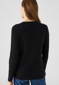 Jersey negro con relieve, de mangas largas y cuello redondo, con tejido texturizado. Fabricado con un material acogedor. Diseño sencillo.