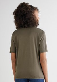 Olivgrünes T-Shirt mit kurzen Ärmeln aus weichem Stoff, mit entspannter Passform und rundem Ausschnitt. Einfaches Design ohne sichtbare Logos oder Verzierungen.