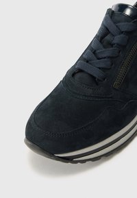 Zapatilla de ante navy con diseño de cordones, acento de cremallera y suela de goma. La punta redondeada y los detalles cosidos realzan la estructura general.