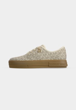 Beżowy niski sneaker ze złotymi oczkami i okrągłą zawieszką MK, wzór z powtarzającym się logo MK oraz brązowa podeszwa z marką Michael Kors.