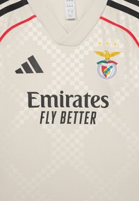Maillot de football gris clair avec un motif texturé à carreaux. Comprend des bandes noires Adidas, le logo Emirates et le blason du club avec trois étoiles.