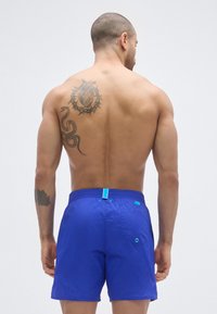 Μπλε ανδρικά μαγιό σορτς με ελαστική μέση, διαθέτουν πίσω τσέπη με μεταλλικό μάτι και αντίθετες τυρκουάζ λεπτομέρειες, ελαφρύ ύφασμα.