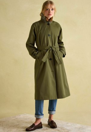 Olive green trench coat with a belted waist, featuring a high collar and button closure. Rolled-up sleeves and plaid lining detail.