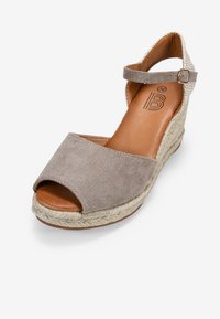 Beige suede wedge sandal featuring an open-toe design, ankle strap, and a braided rope sole. Inner lining is tan leather. Size 36.