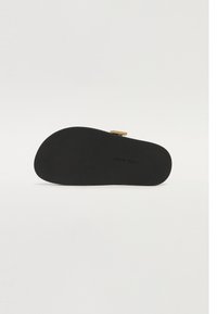 Black sole with a textured finish, featuring a rectangular gold accent. The base has a rounded shape and clear branding. Smooth, matte surface.