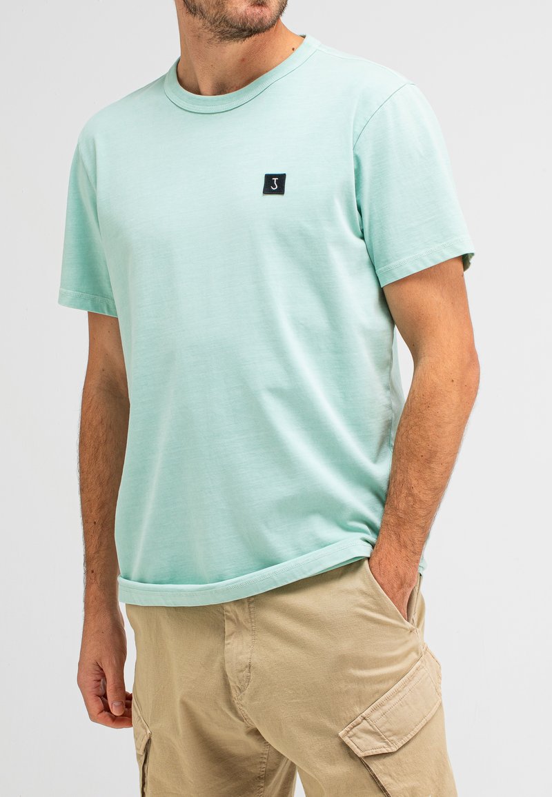 Light mint green cotton t-shirt with a crew neckline and short sleeves. Features a small black square logo on the chest.
