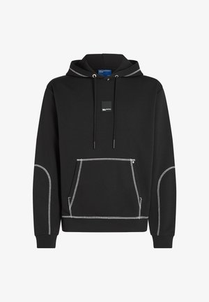 Melnā kapuce, kas izgatavota no gludas auduma, ar priekšējo kangaroo kabatu, baltu šuvju akcentiem un mazu zīmola etiķeti uz krūšu.