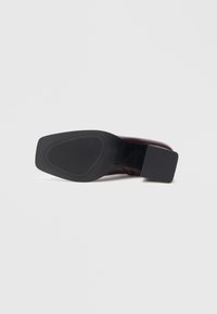 Semelle de chaussure en cuir marron avec une finition lisse, présentant une forme structurée et une semelle extérieure en caoutchouc noir texturé pour une bonne adhérence.