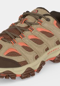 Chaussure de randonnée marron et beige avec des accents orange, semelle robuste, lacets à motifs et logo Merrell sur le côté.