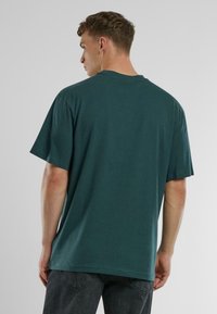 Tengerés kék, oversized póló, kerek nyakkivágással és rövid ujjakkal, puha pamut anyagból készült, áttetsző mintázat nélkül.