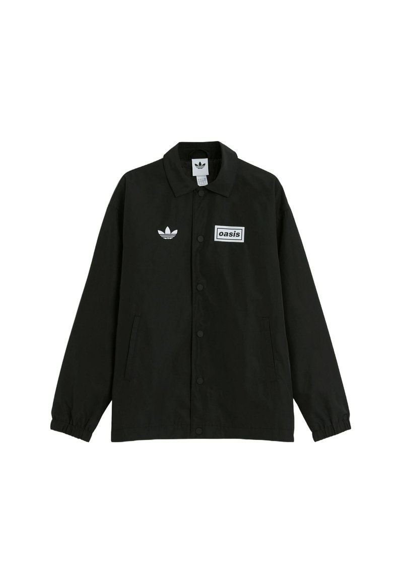 Black button-up jacket made of smooth fabric. Features a white rectangular patch with "oasis" text and Adidas logo on the chest.