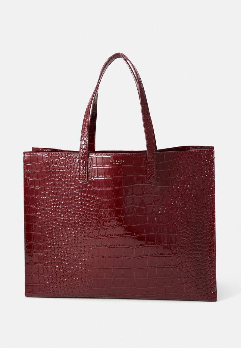 Bolsa tote burgundy com padrão de crocodilo e acabamento brilhante, apresentando duas alças robustas e sem acentos de metal. Forma quadrada.