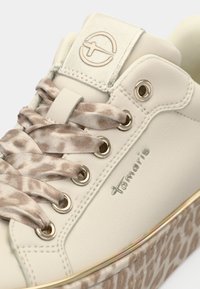 Basket écrue avec lacets en satin à imprimé léopard, œillets argentés, logo sur la languette et motif léopard sur le bord de la semelle.