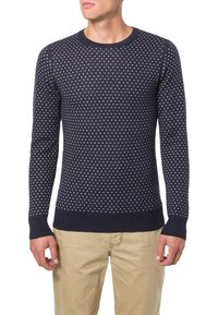 Marinblå tröja med vitt prickmönster, rund halsringning, långa ärmar och ribbade muddar och nederkant. Tillverkad av strukturerad stickad textil.