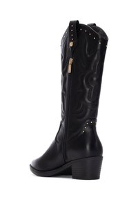 Botas altas de cuero negro con un diseño texturizado, tachuelas doradas, cremallera lateral y suela de tacón apilado. Detalles clásicos de estilo western.