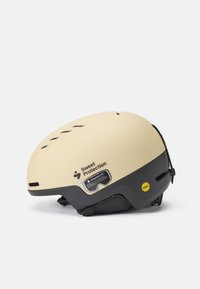 Kask w kolorze kremowym o matowym wykończeniu, czarna dolna część, sloty wentylacyjne oraz system regulacji dopasowania. Posiada etykietę technologii MIPS.
