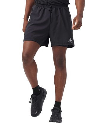 Shorts de sport noirs avec une taille à cordon, fentes latérales et logo sur la jambe gauche, fabriqués en tissu léger et lisse.