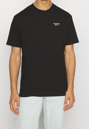 Black short-sleeve t-shirt made of cotton, featuring a small white "CLOSED 24/7" graphic on the left chest area. Crew neck design.