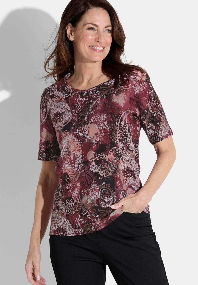 Haut à manches courtes présentant un motif paisley bordeaux et noir. Fabriqué dans un tissu léger et lisse, avec un col rond et une coupe décontractée.