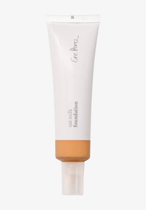Oat milk foundation in a white, squeeze tube. The bottom has a transparent section revealing a light tan liquid. Text reads “Ere Perez.”