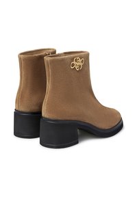 Stivaletti alla caviglia in suede marrone con punta rotonda, tacco grosso nero e accento del logo dorato sul lato; texture liscia e design minimalista.