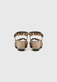 Sandales en imprimé léopard avec des brides noires, talons en liège texturé et dos ouvert. Équipées de brides de cheville ajustables pour un ajustement et un confort optimal.