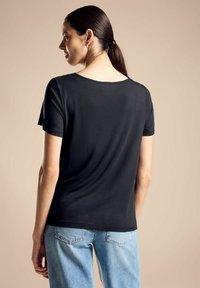 Sort kortærmet T-shirt med rund halsudskæring, lavet af et glat stof, kombineret med lyseblå denim jeans. Enkel design, ingen mønstre.