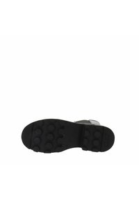 Suela de bota negra con patrón de tread hexagonal y una correa con hebilla visible en el lado.