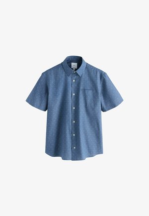 Chemise bleue à manches courtes avec motif de petits pois blancs et poche poitrine gauche, présentée sur fond blanc.