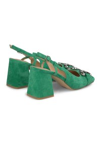 Zielone zamszowe szpilki typu slingback na blokowym obcasie, z dekoracyjnym metalowym łańcuchem z przodu oraz regulowanym paskiem na kostce.