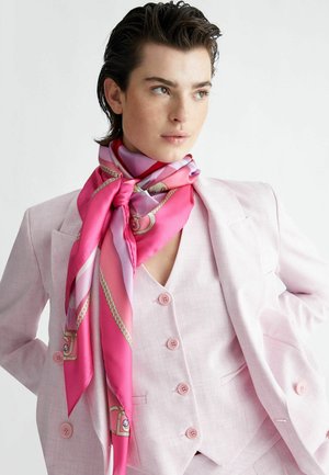 Pañuelo de seda rosa con una textura suave, que presenta un degradado de tonos rosas y un patrón de cadenas, atado alrededor de un cuello debajo de un traje rosa claro.