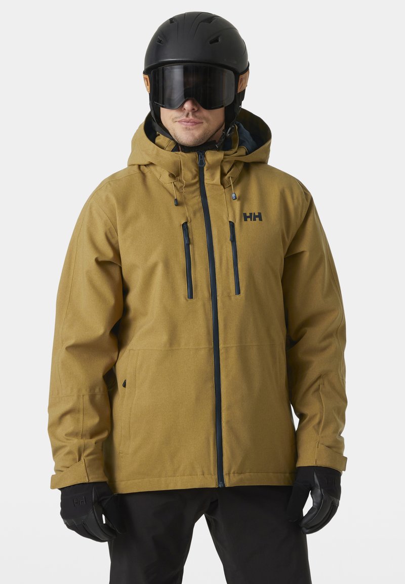 Giacca da sci marrone con cappuccio, cerniere nere e due tasche frontali. Finitura opaca, indossata con casco nero e guanti.