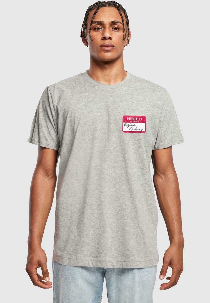 Camiseta gris de algodón, con cuello redondo y mangas cortas. Diseño notable de etiqueta roja con el texto "HELLO" en el lado izquierdo del pecho.