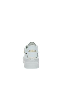 Sneaker bianco con un esterno in pelle liscia, logo dorato sul tallone e sottili accenti dorati. Punta arrotondata e collarino imbottito per il comfort.