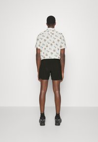 Short-sleeve shirt with ice cream and dessert patterns, back view; paired with black shorts, worn with gray sneakers and black socks.