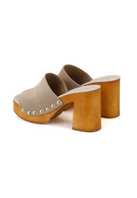 Beige leren clogs met een glad ontwerp, open teen en chunky houten hak. Voorzien van metalen studs langs de zijkant voor extra detail.