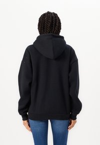 Sweatshirt preto com capuz, de corte relaxado, com punhos e barra canelados. Apresenta uma textura macia e sem logótipos ou padrões visíveis.