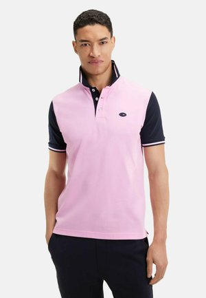 Polo à manches courtes de couleur rose clair avec un col marine. Doté d'un plastron à trois boutons et d'un logo sur la poitrine. Tissu en mélange de coton.